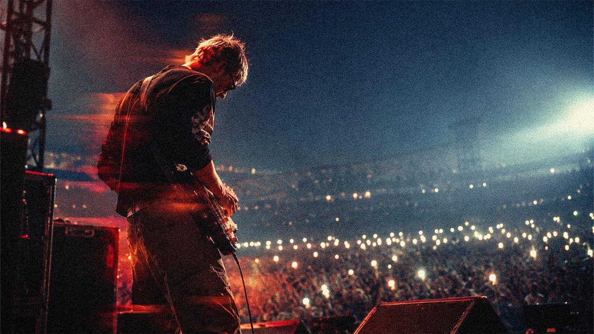 Independent artist playing guitar to a stadium crowd of phone lights, superfans an email list for musicians can turn into direct-to-fan buyers